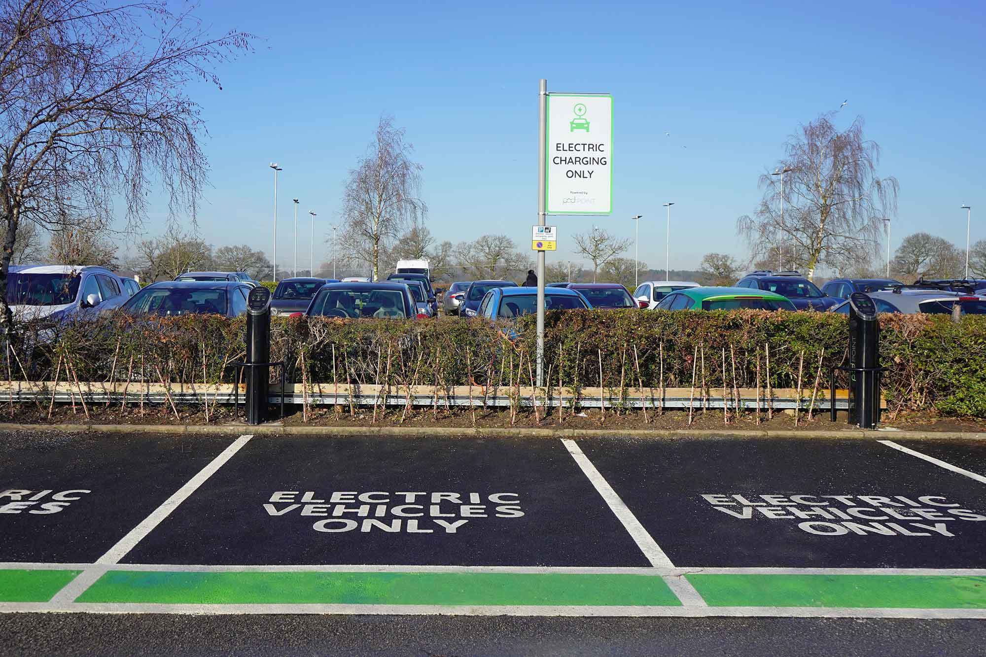 Two Pod Point twin chargers in a car park, with clearly signed EV charging bays