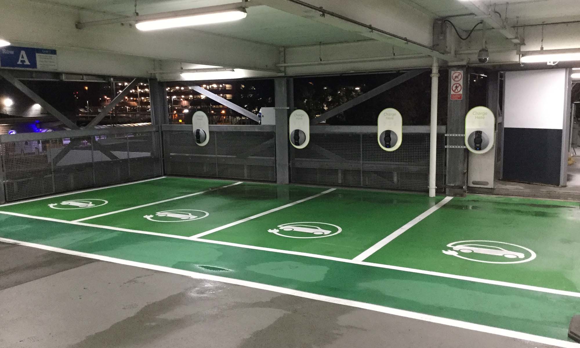 A wide shot of 4 indoor green EV parking bays, with 4 Pod Point Solo 3's installed for each bay