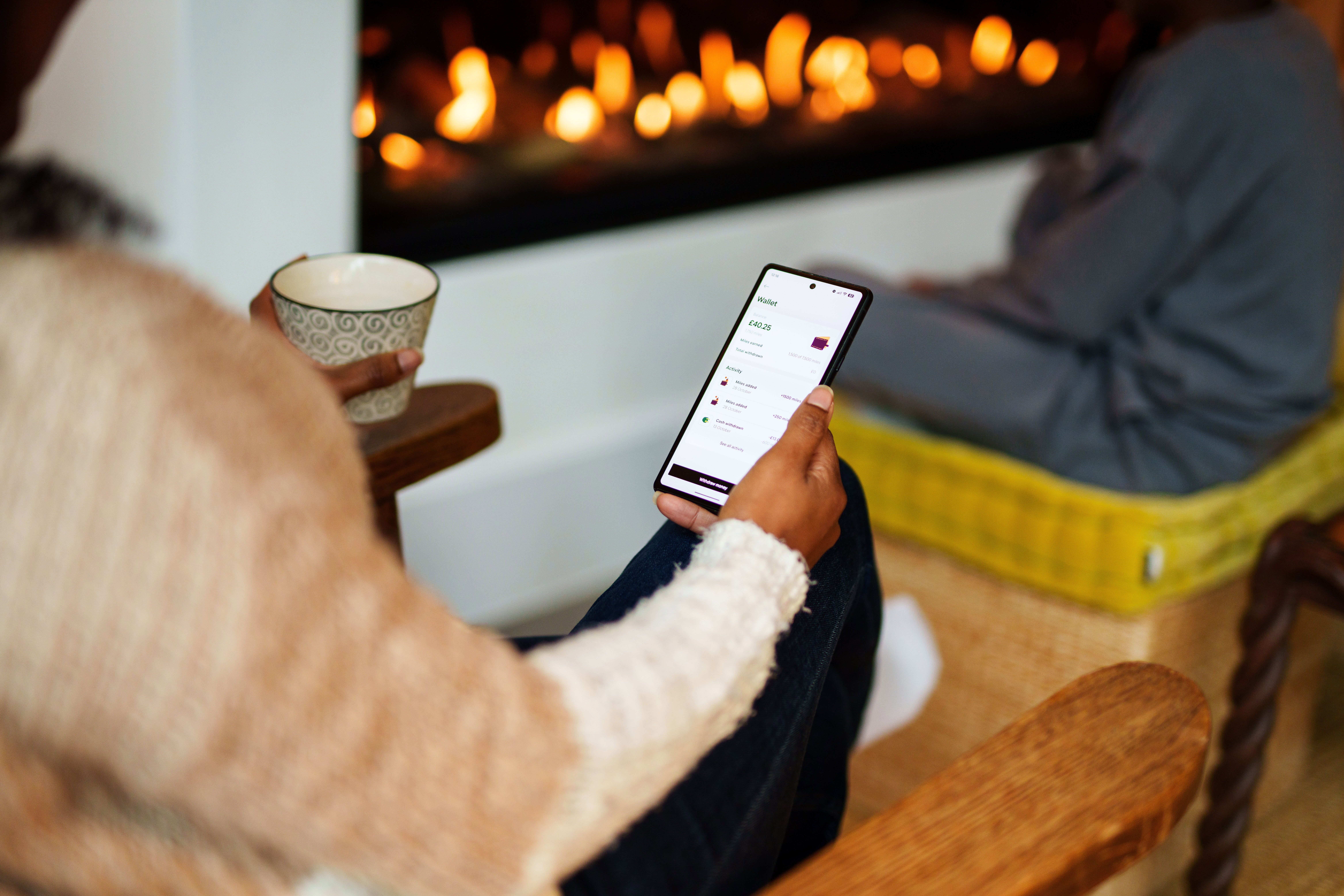 Lady using Pod App by a fireplace