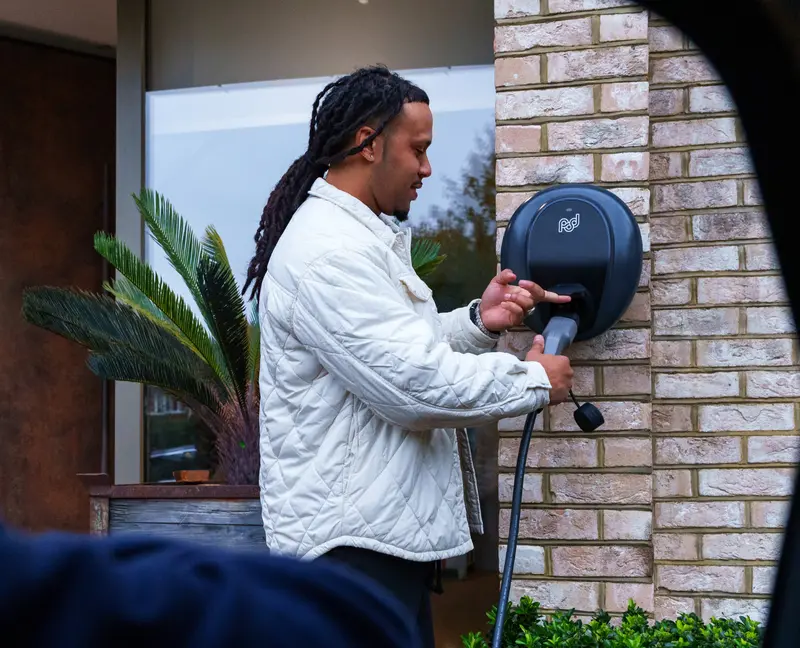 person plugging cable into pod point ev charger