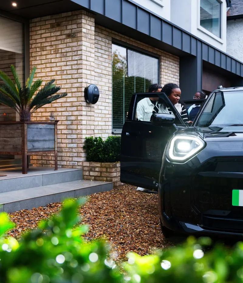 Family getting into EV with Pod Point in background