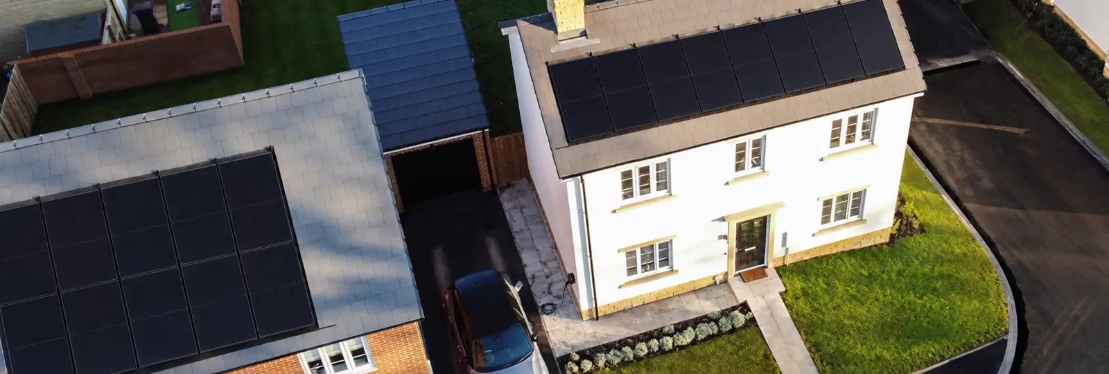 Aerial view of house with solar panels and EV charging on driveway