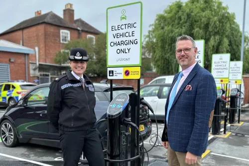 Pod Point sales team member standing with police officer from West Mercia force in front of Pod Point chargers